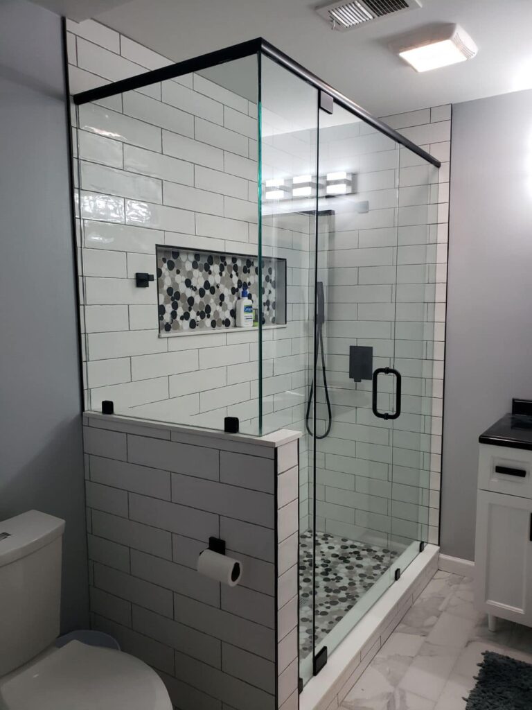 Glass shower door enclosure with custom white and black tiles